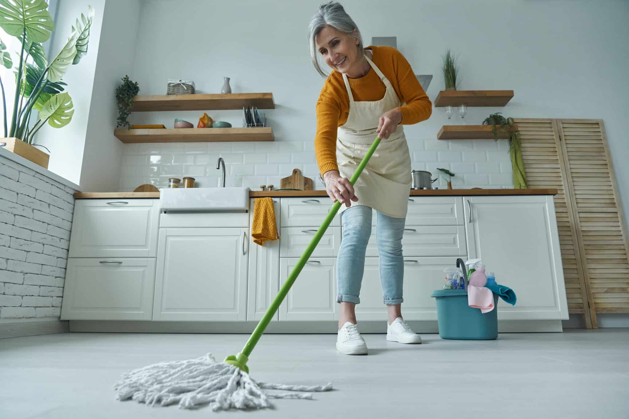 full-length-of-senior-woman-cleaning-floor-with-mo-2022-12-16-14-23-34-utc-scaled.jpg